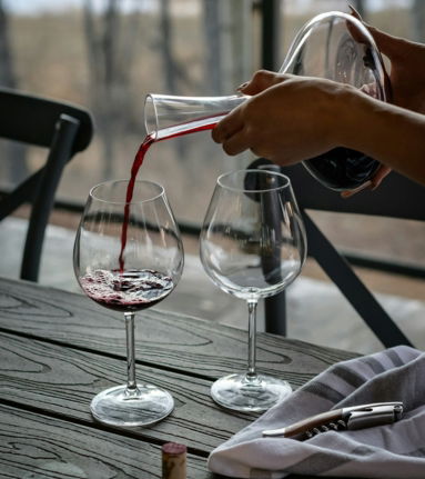 person pouring wine from decanter on wineglass